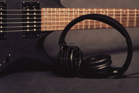 Foto de Guitarra eléctrica negra con auriculares sobre fondo oscuro para temas musicales y dibujos. Equipo de compositor de música - Imagen libre de derechos