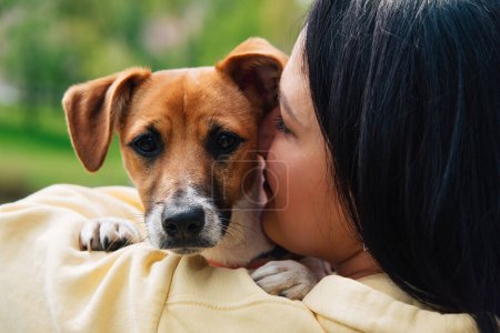 Foto de Mujer y un perro retratos de cerca. La mujer sostiene a un perro en sus brazos, abraza. Jack Russell Perro Terrier. Hermoso paisaje natural de verano colorido - Imagen libre de derechos