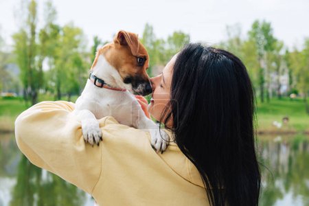 Foto de Mujer y un perro retratos de cerca. La mujer sostiene a un perro en sus brazos, abraza. Hermoso paisaje natural de verano colorido - Imagen libre de derechos