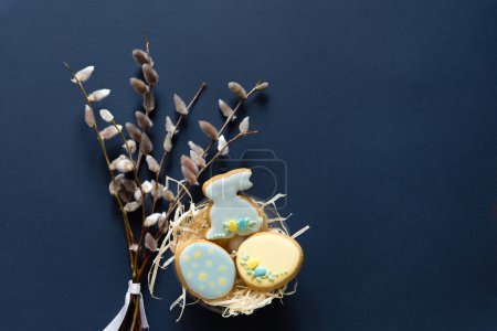 Foto de Spring pussy willow branches and gingerbread cookies. Easter minimalist concept on blue background with copy space for text. - Imagen libre de derechos