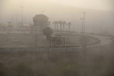 Foggy sunrise in the morning on the Mediterranean Sea, sea view, beach and park with palm trees. Vacations and relaxation by the sea.
