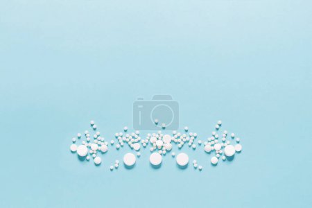 Téléchargez les photos : Pilules blanches éparpillées sur fond bleu. Maquette pour des offres spéciales comme la publicité, fond web ou d'autres idées. Espace de copie - en image libre de droit