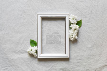 Téléchargez les photos : Carte de la fête des mères avec cadre photo vierge et fleur blanche sur fond de lin gris - en image libre de droit