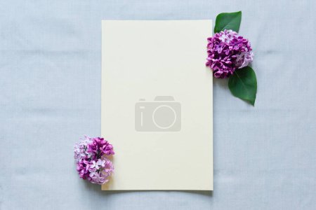 Téléchargez les photos : Maquette feuille de papier vierge avec fleurs lilas, vue du dessus, modèle carte vide plat avec espace de copie - en image libre de droit