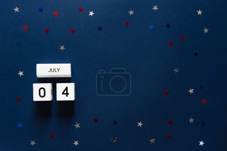 Téléchargez les photos : Fête de l'indépendance américaine, vue du dessus sur cubes en bois calendrier 4 juillet sur fond bleu avec des étoiles confettis - en image libre de droit
