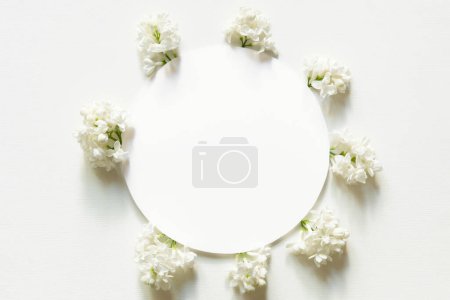 Téléchargez les photos : Cercle blanc avec des fleurs lilas sur fond blanc. Couché à plat, vue de dessus. Bonne fête des mères, fête des femmes ou anniversaire, composition du mariage. - en image libre de droit