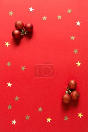 Téléchargez les photos : Composition de Noël et du nouvel an avec boules rouges de Noël et étoiles de confettis d'or. Fond rouge. Vue de dessus, plan plat. Espace vide pour espace de copie - en image libre de droit