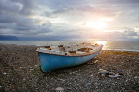 Foto de Antiguo barco de pesca abandonado roto en la orilla del mar al atardecer. - Imagen libre de derechos