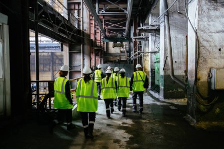 Téléchargez les photos : Groupe de travailleurs en uniforme marchant le long du couloir de l'usine. - en image libre de droit