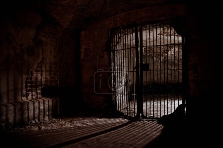 Téléchargez les photos : Lumière rayonnante de grille de fer dans une ancienne cave. - en image libre de droit