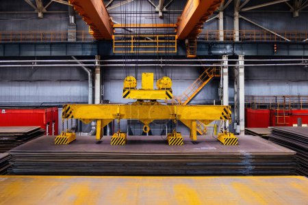 Overhead crane with magnetic grippers lifting steel sheets.
