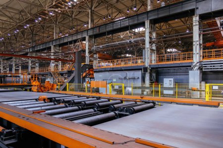 Stahlblech bewegt sich auf Rollenbahn in metallverarbeitender Werkstatt.