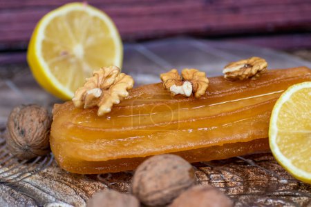 Téléchargez les photos : Gâteau sucré turc appelé tulumba, servi dans une assiette avec des tranches de citron et de noix autour, sur une table en bois massif - en image libre de droit