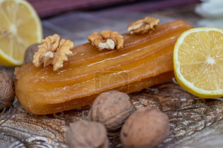 Turkish sweet cake called tulumba, served at plate with sliced of lemon and nuts around, on massive wooden table