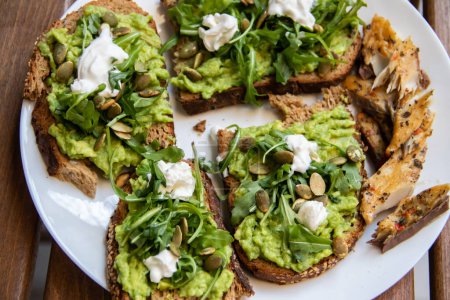 Smashed avocado on Toast with Labneh, Lemon, Parsley, Cheese, Edamame and different dried seeds, sunflower and pumpkin, very healthy and vegan green breakfast made by organic ingredients