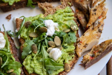 Smashed avocado on Toast with Labneh, Lemon, Parsley, Cheese, Edamame and different dried seeds, sunflower and pumpkin, very healthy and vegan green breakfast made by organic ingredients