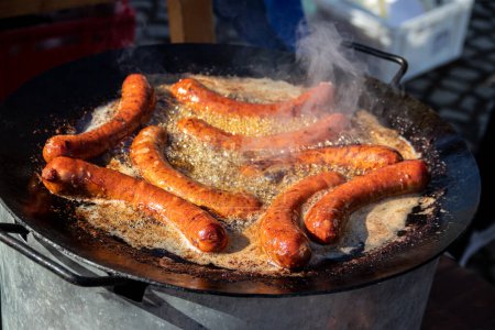 Street-Food-Kochen auf der großen Pfanne, leckere hausgemachte Würstchen auf der großen kommerziellen Grillplatte, Food-Festival auf dem Land in Serbien