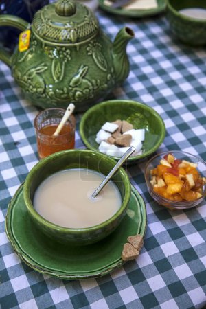 Téléchargez les photos : Petit déjeuner en road trip en France avec vaisselle traditionnelle rustique en céramique verte, tasse de café, compote de fruits et sucre - en image libre de droit