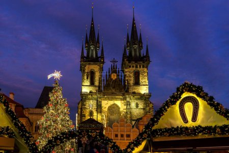 Illuminated Christmas tree and famous Tyn church on Old Town Square under evening sky in Prague, Czech Republic.