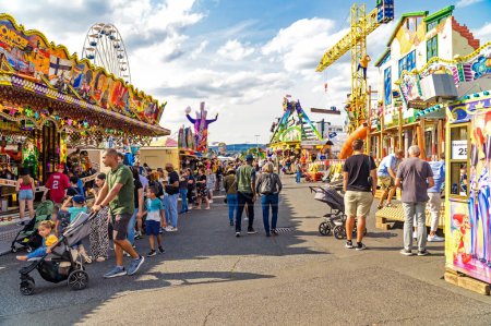 Photo for WIESBADEN, HESSE, GERMANY - 07-03-2023- People walk the center with amusement park rides at the German American Friendship Festival in Wiesbaden. - Royalty Free Image