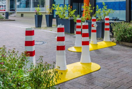 Foto de Pilonas de seguridad rojas y blancas en la ciudad rodean las plantas verdes - Imagen libre de derechos