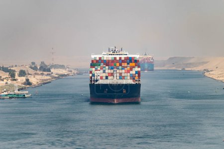 Huge cargo ships navigate through Suez Canal. Shipping canal in Egypt. Concept of transportation and logistics.
