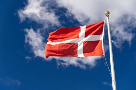 Dänische Flagge vereinzelt am blauen Himmel mit Wolken. Aus nächster Nähe Flagge von Dänemark schwenken