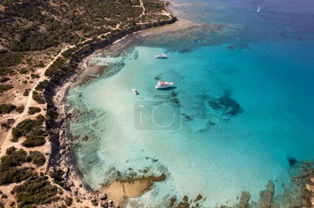 Téléchargez les photos : Vue aérienne de la plage de lagune bleue de Chypre île, parc national de Paphos. Eau cristalline avec quelques bateaux de tourisme flottant. Parc forestier national d'Akamas - en image libre de droit