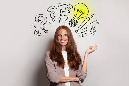 Photo for Smiling brunette woman with yellow light bulb, question marks above her head. Idea, brainstorming, business stratgy, thinking concept - Royalty Free Image