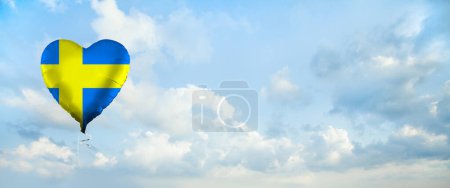 Foto de Bandera de Suecia sobre globo en forma de corazón sobre fondo de nubes de cielo. Educación, caridad, emigración, viajes y aprendizaje. Concepto de idioma sueco - Imagen libre de derechos