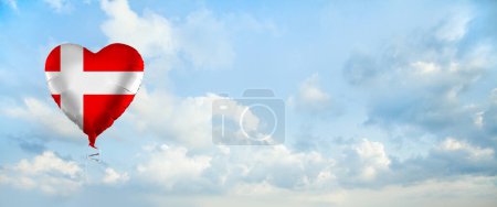 Foto de Flag of Denmark on heart-shaped balloon against sky clouds background. Education, charity, emigration, travel and learning. Danish language concept - Imagen libre de derechos