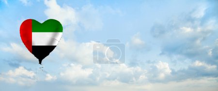 Foto de Flag of United Arab Emirates on heart-shaped balloon against sky clouds background. Education, charity, emigration, travel and learning. UAE language concept - Imagen libre de derechos