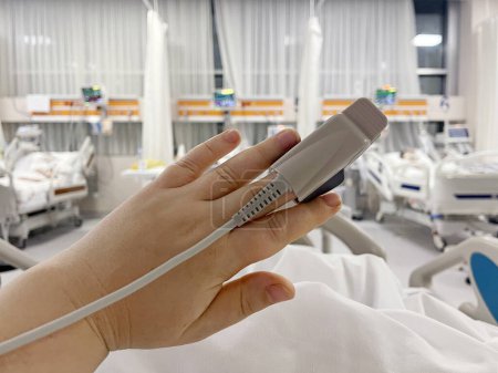 Foto de En el hospital paciente enfermo en la cama. El equipo de monitor de frecuencia cardíaca está en su dedo, primer plano de la mano - Imagen libre de derechos