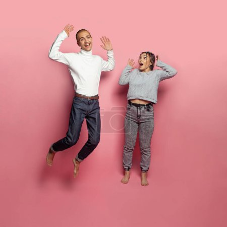 Photo for Jumping man and woman having fun on brigtht pink studio wall background - Royalty Free Image