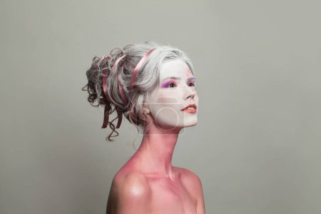 Téléchargez les photos : Belle femme avec coiffure et maquillage fantaisie parfaite sur fond gris. Carnaval et Halloween mode beauté portrait - en image libre de droit