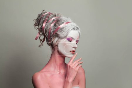 Téléchargez les photos : Actrice magique avec maquillage de scène, corps peint en rose et coiffure parfaite sur fond de bannière grise, portrait - en image libre de droit