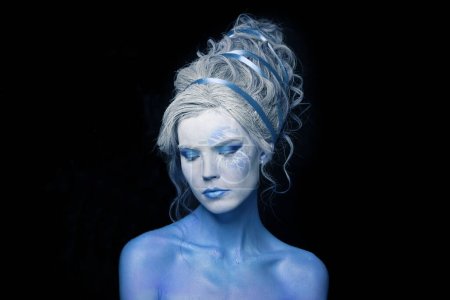 Fashion beauty portrait of young nice model woman with blue skin, stage makeup and hairstyle on gray background