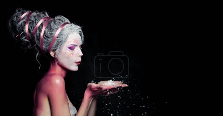 Pretty model woman with creative makeup and white snow on black background