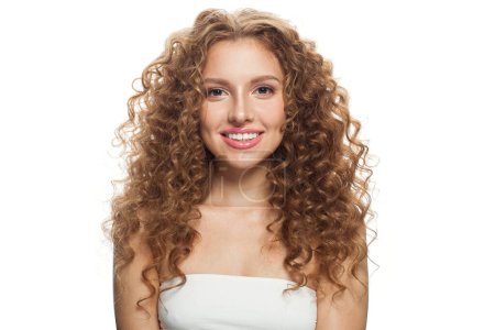 Positive junge Frau mit natürlichem Make-up, klarer, frischer Haut und gewellter Frisur auf weißem Hintergrund