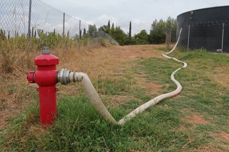 Foto de Boca de incendios con manguera conectada al tanque de agua. - Imagen libre de derechos