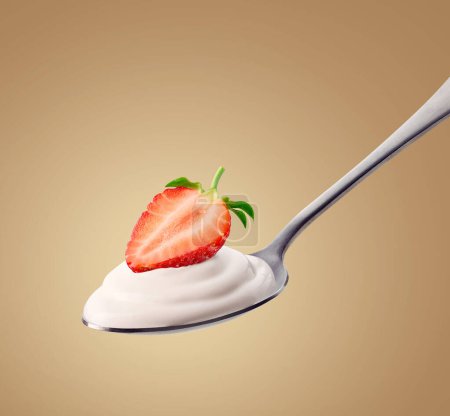 Photo for Silver spoon of fresh greek yogurt and strawberry on light brown background - Royalty Free Image