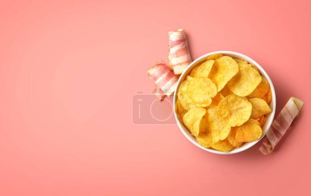 Foto de Cuenco de papas fritas crujientes o patatas fritas con sabor a tocino sobre fondo rosa, vista superior, espacio vacío para el texto - Imagen libre de derechos