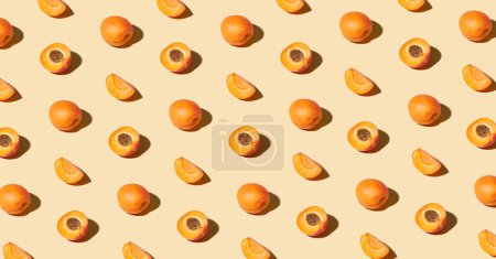 Téléchargez les photos : Modèle coloré d'abricots frais mûrs entiers et tranchés. Concept minimaliste de fruits du soleil tendance sur fond orange clair - en image libre de droit