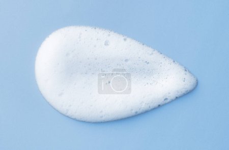 Foto de Espuma limpiadora blanca para el cuidado de la piel sobre fondo azul claro. Jabón, champú o gel de ducha textura de espuma, primer plano, vista superior - Imagen libre de derechos