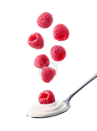Téléchargez les photos : Cuillère de yaourt grec frais et framboises tombantes isolées sur fond blanc - en image libre de droit