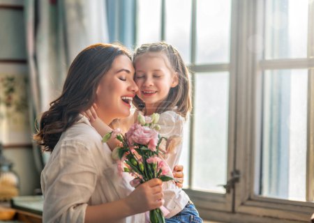 Foto de Feliz día de la madre. Hija niña felicitando a su madre y dándole ramo de flores. - Imagen libre de derechos
