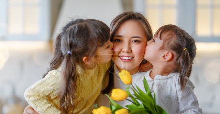 Téléchargez les photos : Bonne fête des mères. Filles enfants félicitant mère et donnant son bouquet de fleurs. - en image libre de droit