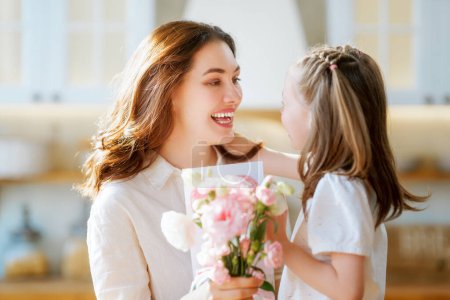 Téléchargez les photos : Bonne fête des mères. Enfant fille félicitant sa mère et lui donnant un bouquet de fleurs. - en image libre de droit