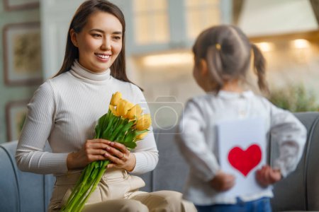 Téléchargez les photos : Bonne fête des mères. Enfant fille félicitant sa mère et lui donnant un bouquet de fleurs. - en image libre de droit