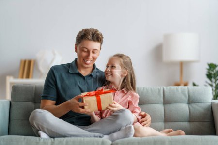 Photo for Happy father's day! Child daughter congratulating dad and giving him gift box. Daddy and girl smiling and hugging. Family holiday and togetherness. - Royalty Free Image